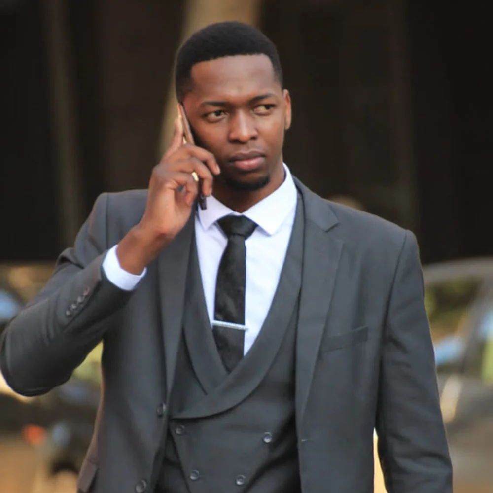 Farai Chimbwedza taking a phone call while wearing a suit