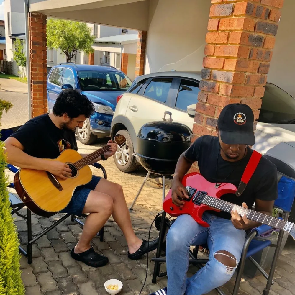 Farai Chimbwedza playing a read guitar with his friend playing acoustic guitar